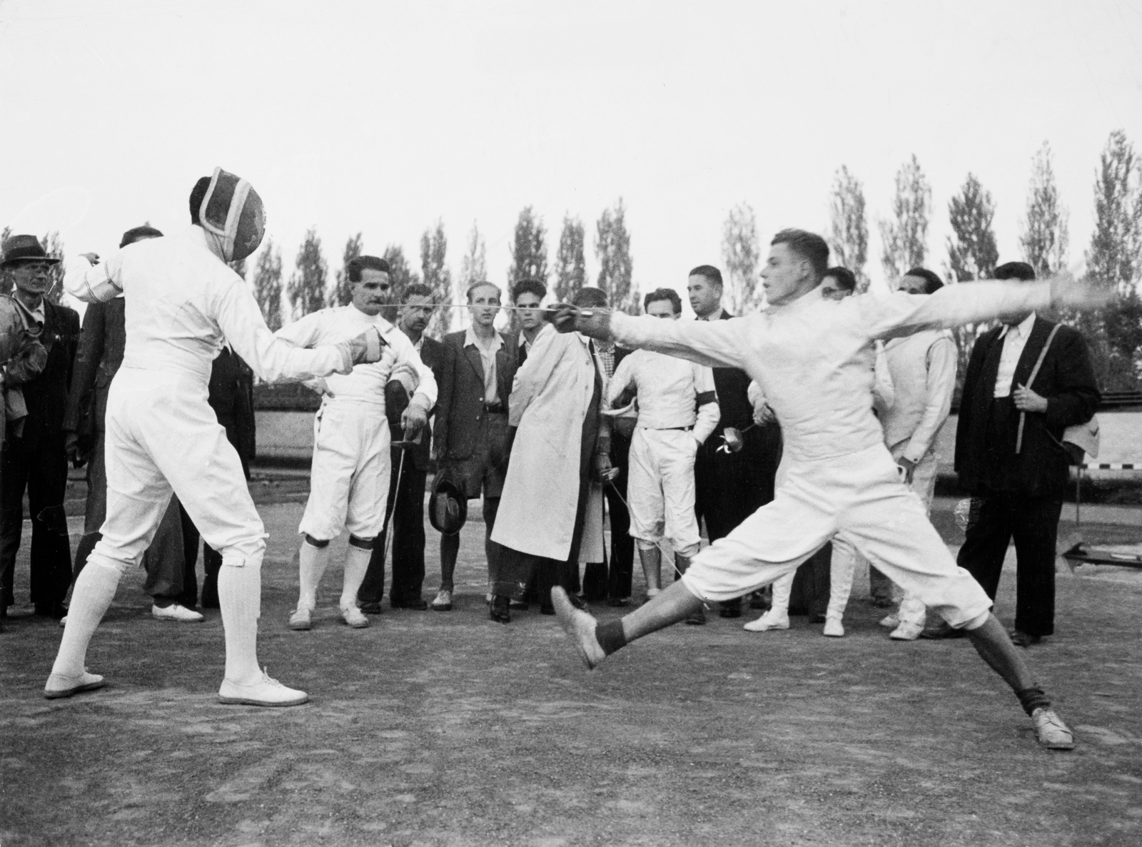 [Vívók és közönségük, közöttük (a fejvédjét tartó) Berczelly Tibor olimpiai bajnok kardvívó egy sportbemutatón, Budapest], 1948. szeptember, Robert Capa, Courtesy International Center of Photography | [Fencers and spectators including Olympic champion saber fencer Tibor Berczelly (holding helmet) at a sports demonstration, Budapest] September 1948, Robert Capa, Courtesy International Center of Photography